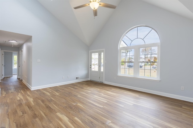 spare room with light wood-type flooring, high vaulted ceiling, and a healthy amount of sunlight