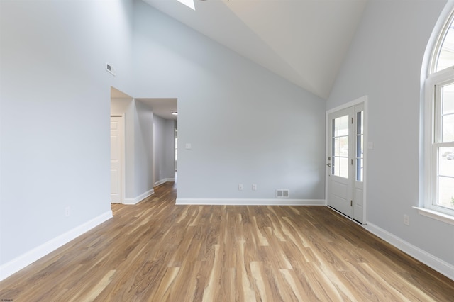 unfurnished room featuring light hardwood / wood-style floors, high vaulted ceiling, and french doors