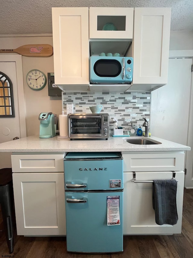 kitchen with a textured ceiling, decorative backsplash, white cabinetry, and sink