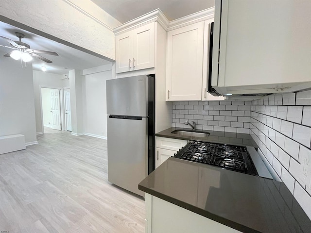 kitchen with white cabinetry, sink, ceiling fan, stainless steel fridge, and black gas stovetop