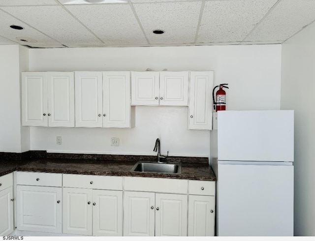 kitchen featuring white cabinets, white refrigerator, a paneled ceiling, and sink