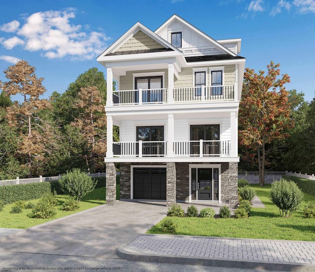 view of front of home featuring stone siding, a balcony, driveway, and a front yard