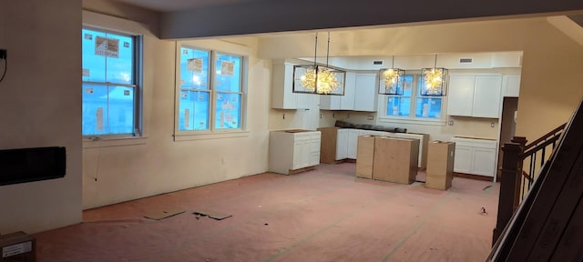 kitchen with white cabinetry, a center island, visible vents, and pendant lighting