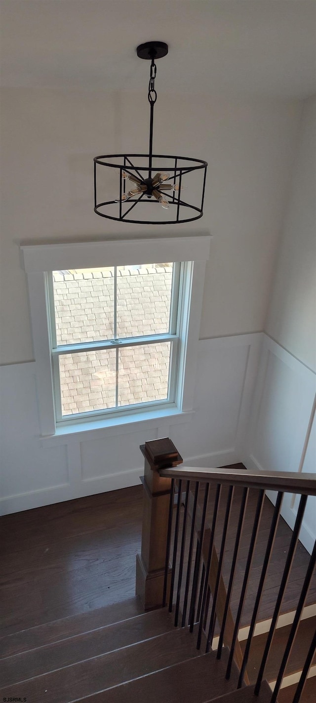 stairway with a notable chandelier and wood finished floors