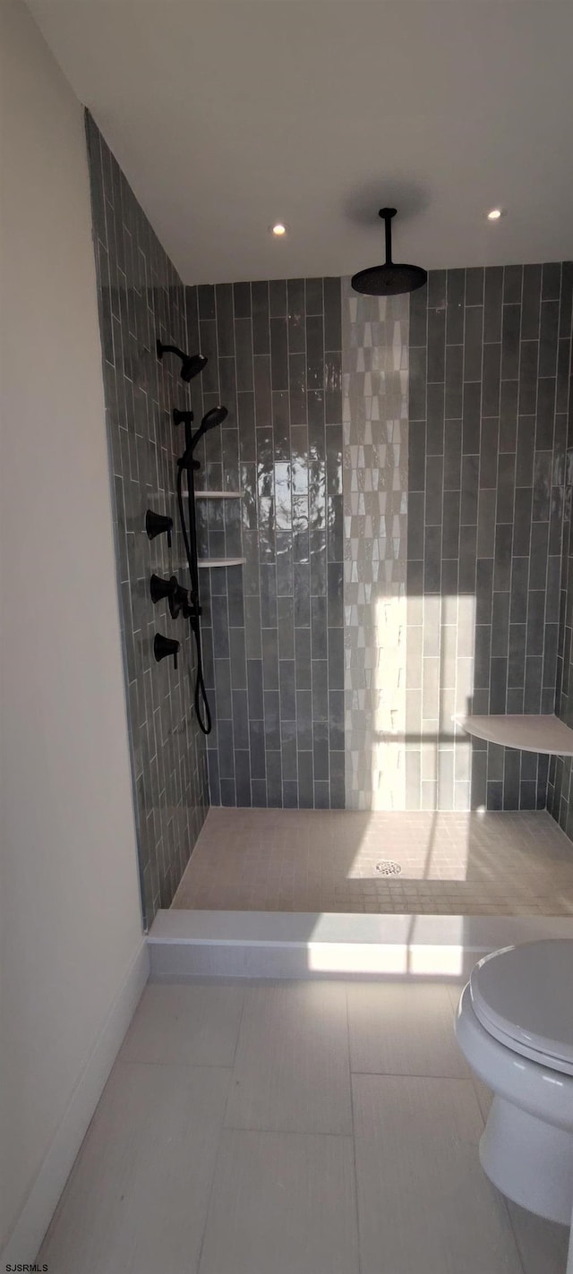 full bath featuring tile patterned flooring, tiled shower, and toilet