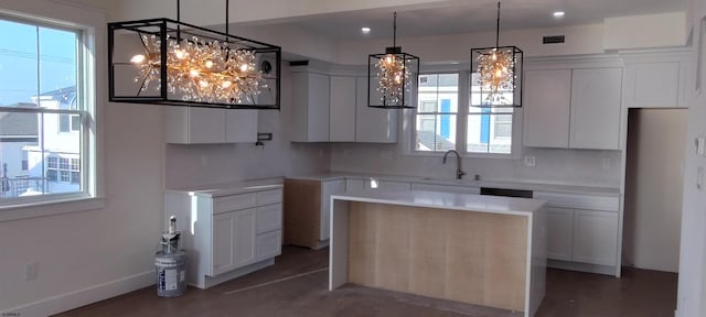 kitchen with visible vents, pendant lighting, a sink, a center island, and white cabinets