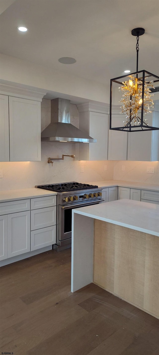 kitchen with dark wood finished floors, stainless steel range, wall chimney range hood, and light countertops