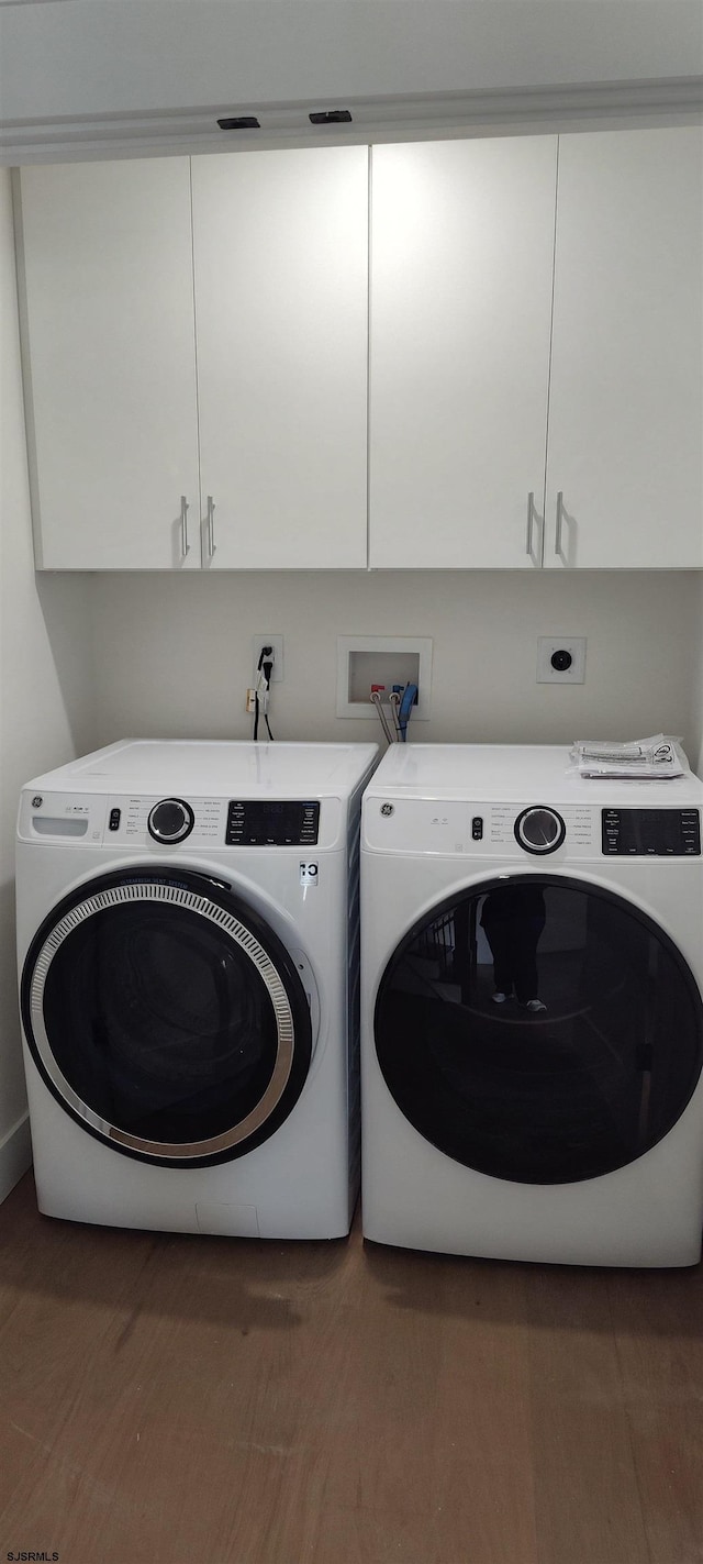 laundry room featuring wood finished floors, cabinet space, and washing machine and dryer