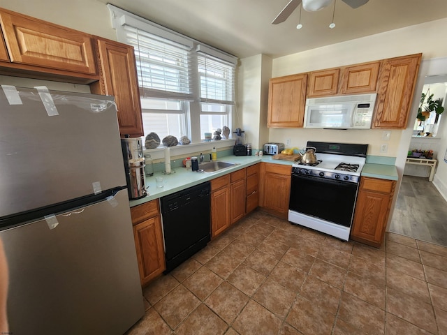 kitchen featuring dark tile patterned flooring, ceiling fan, white appliances, and sink