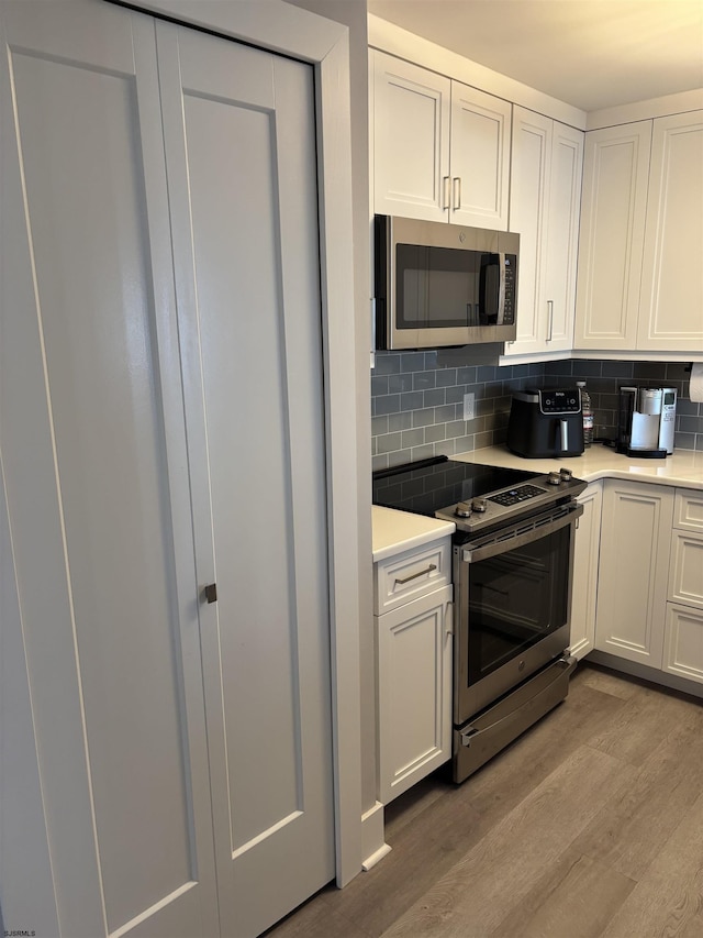 kitchen featuring backsplash, light hardwood / wood-style floors, white cabinetry, and stainless steel appliances