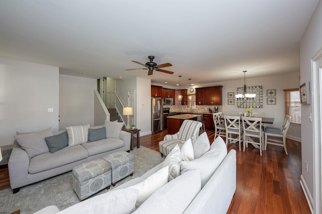 living room featuring dark wood-type flooring and ceiling fan with notable chandelier