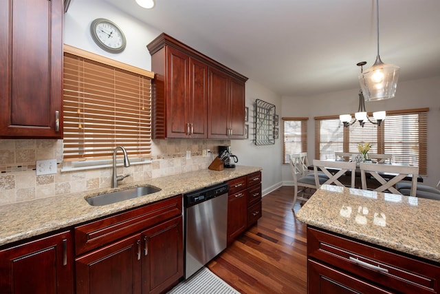 kitchen featuring light stone counters, stainless steel dishwasher, sink, dark hardwood / wood-style floors, and hanging light fixtures