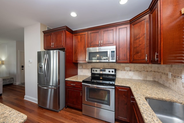 kitchen with dark wood-type flooring, sink, decorative backsplash, appliances with stainless steel finishes, and light stone counters