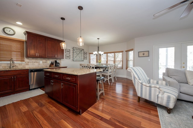 kitchen with sink, stainless steel dishwasher, backsplash, decorative light fixtures, and a breakfast bar