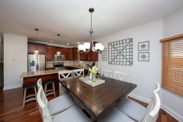 dining area featuring dark wood-type flooring and an inviting chandelier