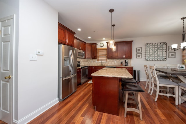 kitchen featuring decorative light fixtures, a kitchen island, decorative backsplash, and appliances with stainless steel finishes