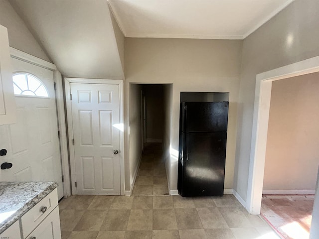 kitchen featuring white cabinets, black refrigerator, and vaulted ceiling