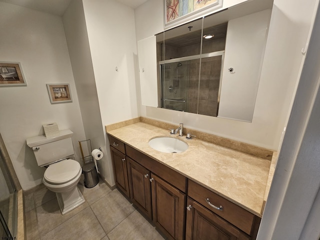 bathroom featuring toilet, vanity, tile patterned floors, and a shower with door