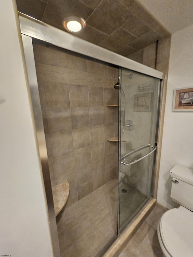 bathroom with toilet and a shower with shower door