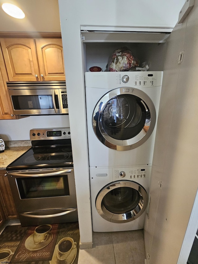 washroom featuring dark tile patterned flooring and stacked washer / dryer