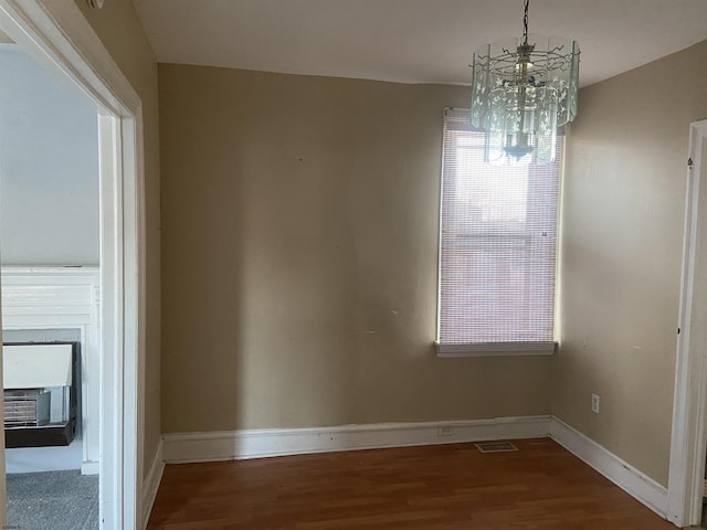 unfurnished dining area with hardwood / wood-style floors and an inviting chandelier