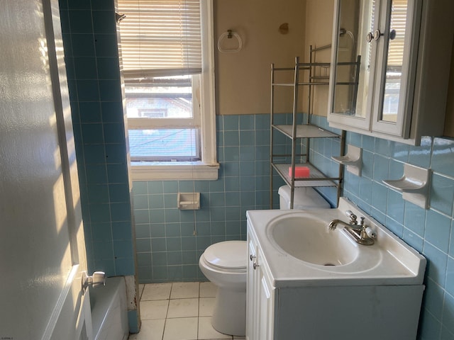 bathroom with tile patterned flooring, a bath, toilet, vanity, and tile walls