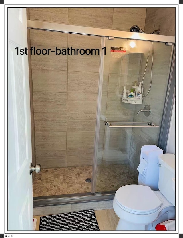 bathroom featuring toilet and a shower with shower door