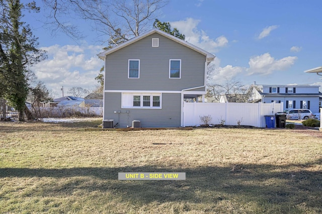 rear view of property featuring central AC unit and a yard