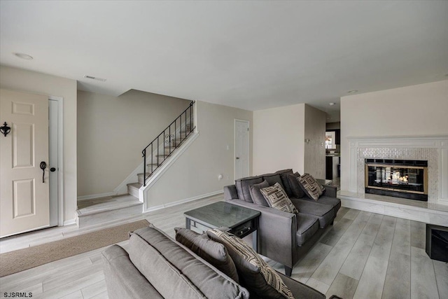 living room featuring light hardwood / wood-style flooring and a tiled fireplace