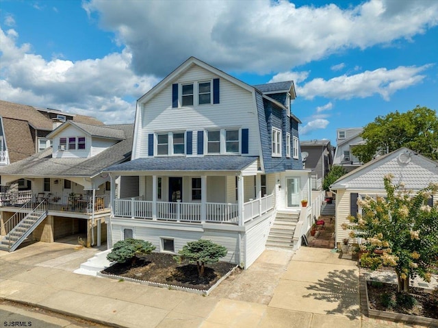 view of front of property featuring a shingled roof, covered porch, driveway, and stairway