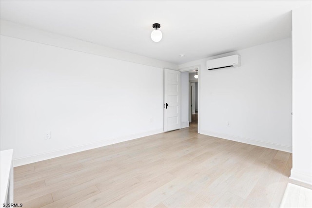 spare room featuring light wood-style floors, baseboards, and an AC wall unit