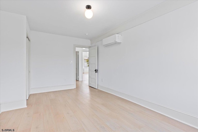 unfurnished room featuring light wood finished floors, baseboards, and an AC wall unit