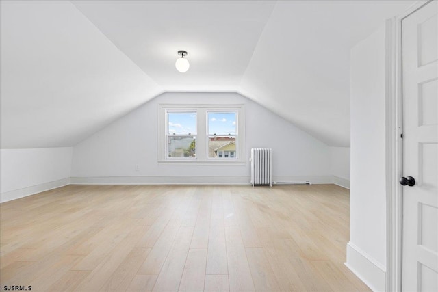 bonus room with lofted ceiling, radiator heating unit, light wood-style flooring, and baseboards