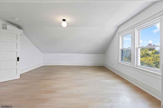 bonus room with vaulted ceiling, light wood-type flooring, and baseboards