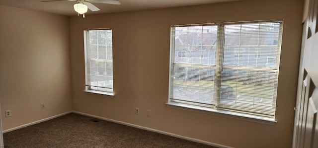 spare room featuring ceiling fan and dark carpet