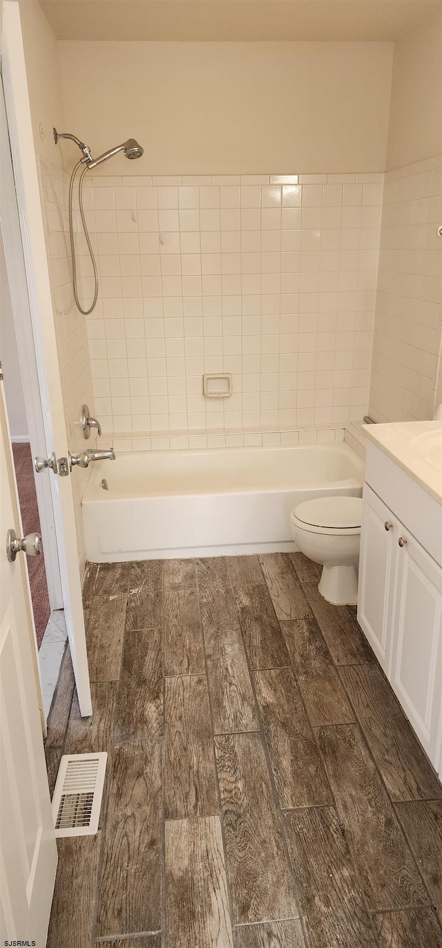 full bathroom with vanity, tiled shower / bath combo, and toilet