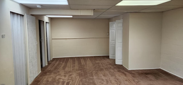 hallway featuring a paneled ceiling and dark carpet