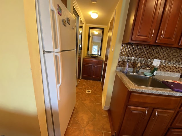 kitchen featuring decorative backsplash, light tile patterned floors, white fridge, and sink