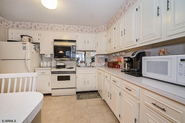 kitchen featuring white appliances, light countertops, a textured ceiling, and white cabinetry