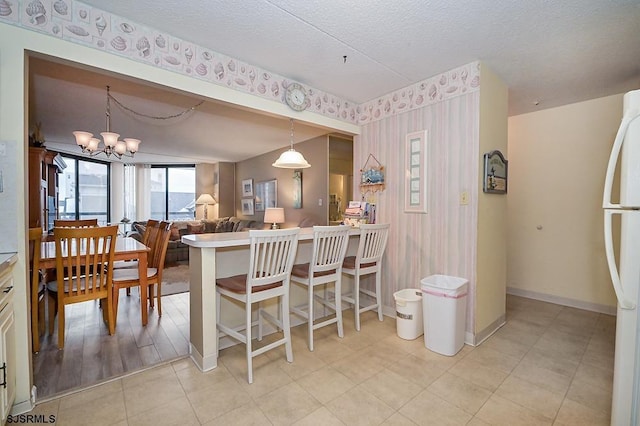 dining space with a chandelier, a textured ceiling, baseboards, and wallpapered walls