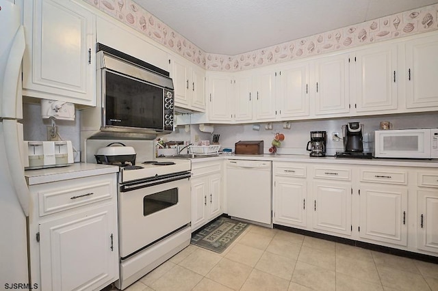 kitchen with light countertops, white appliances, white cabinetry, and light tile patterned flooring