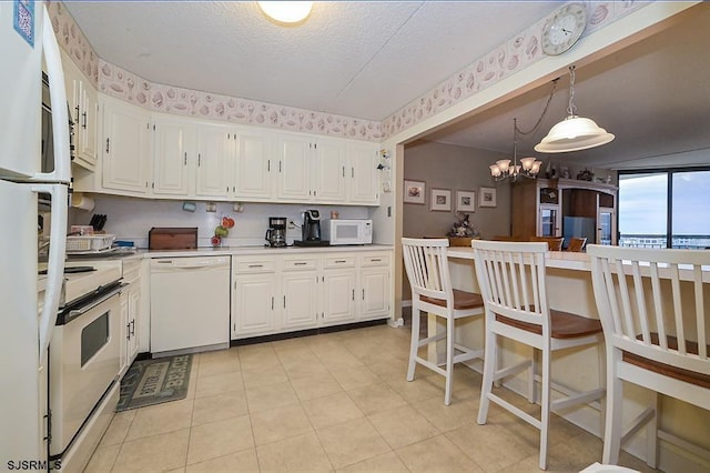 kitchen with light countertops, white cabinets, a textured ceiling, a chandelier, and white appliances