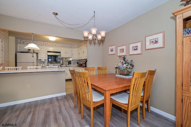 dining area with an inviting chandelier, baseboards, and wood finished floors