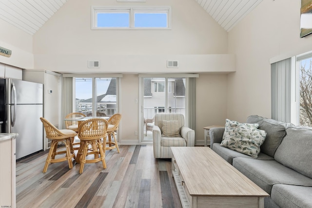 living room featuring wood ceiling, high vaulted ceiling, and light hardwood / wood-style floors