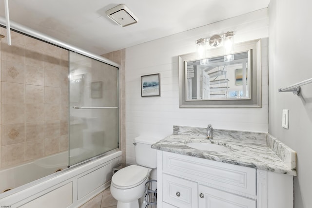 full bathroom featuring tile patterned flooring, vanity, toilet, and bath / shower combo with glass door