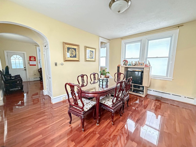 dining area featuring wood-type flooring, a textured ceiling, and a baseboard radiator