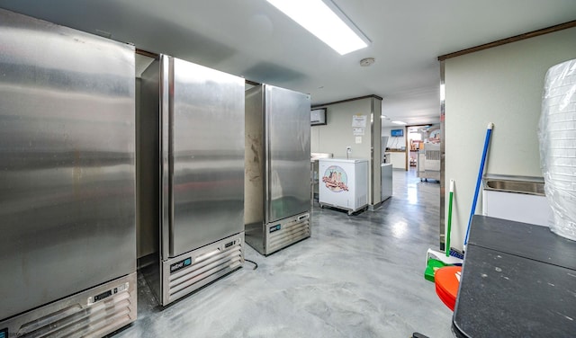 kitchen featuring stainless steel fridge, concrete flooring, and separate washer and dryer