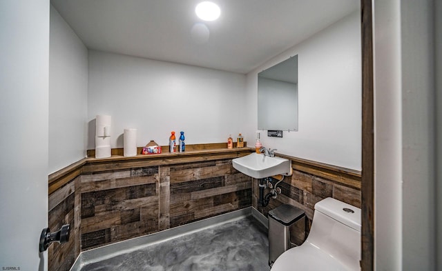 bathroom with toilet, concrete flooring, and sink