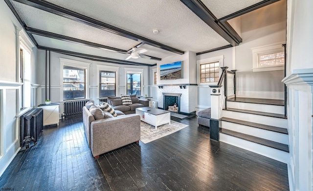 living room featuring beamed ceiling, dark hardwood / wood-style floors, a fireplace, and a textured ceiling