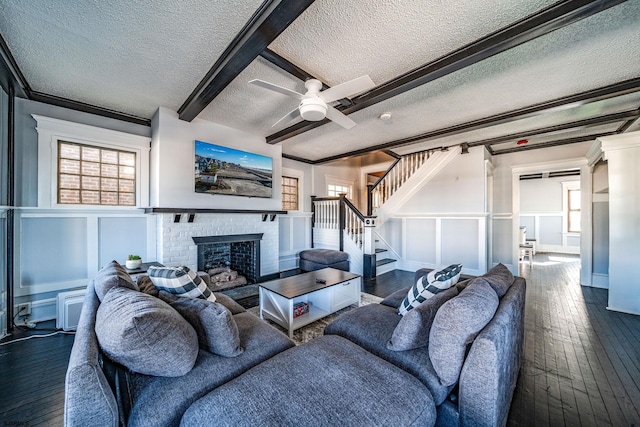 living room with crown molding, a brick fireplace, a textured ceiling, dark hardwood / wood-style flooring, and beamed ceiling